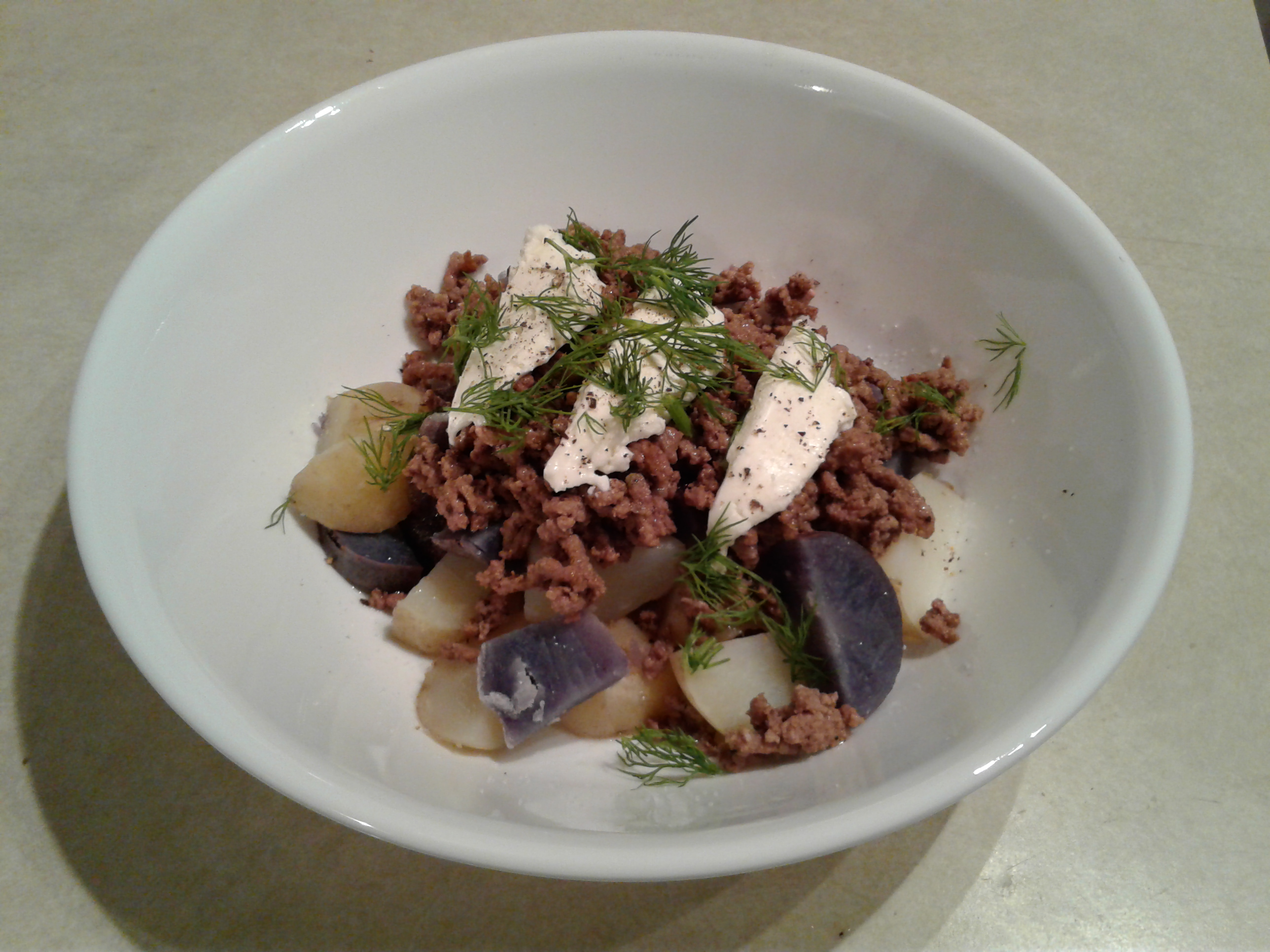 Boiled purple and white potatoes with ground beef and sour cream